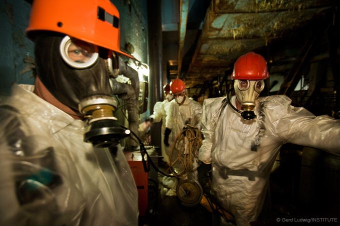 Workers in protective clothing work inside the reactor building